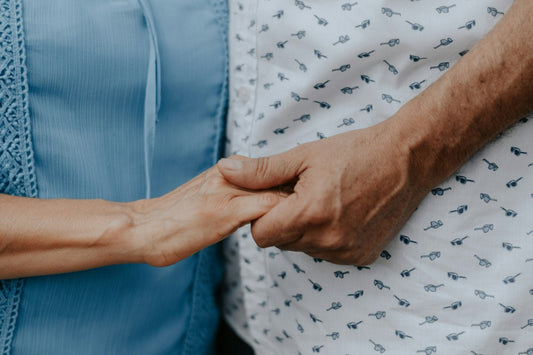 Mano di chi assiste che stringe la mano di una persona anziana
